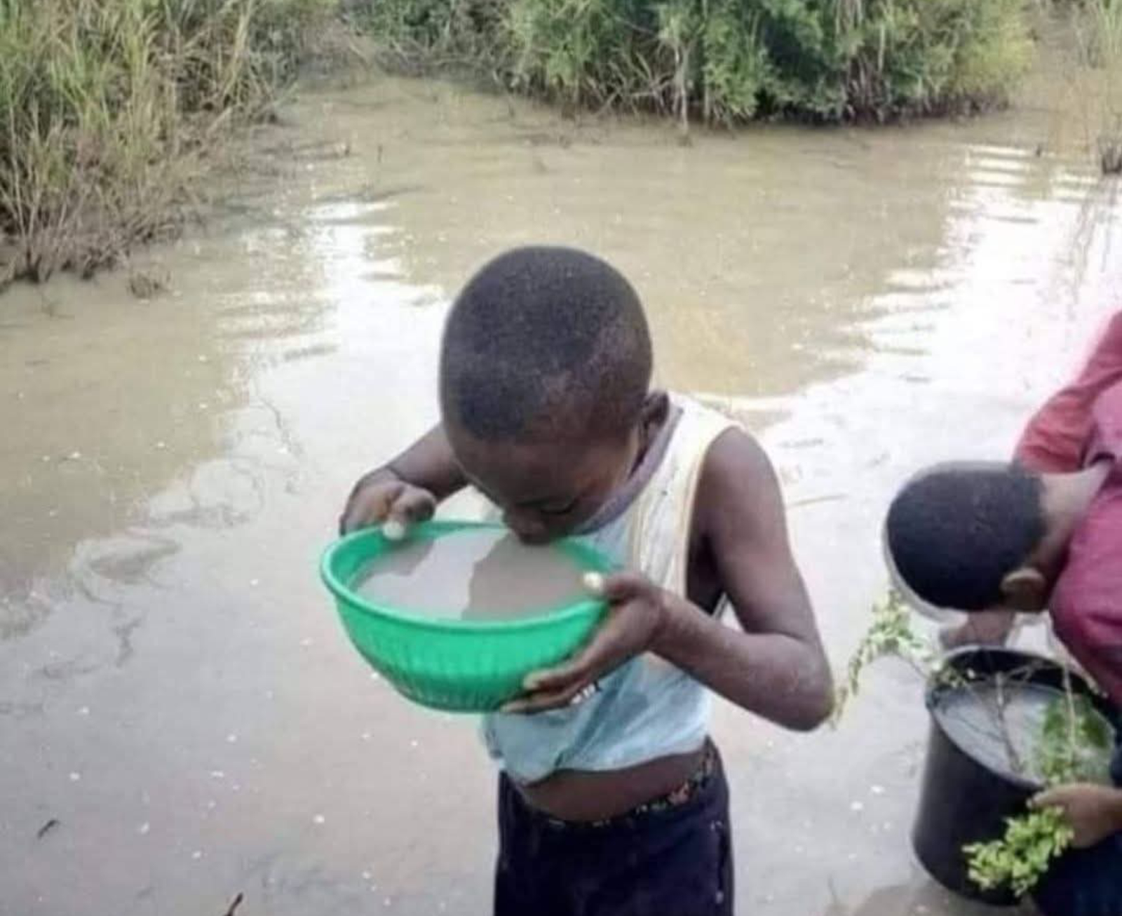 un enfant de l'Atakora boit de l'eau d'un marigot, faute d'eau potable